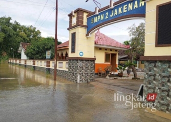 Terlihat masih ada genangan air di depan gerbang masuk SMPN 1 Jakenan, Pati, Jumat, 7 Februari 2025. (Setyo Nugroho/Lingkarjateng.id)