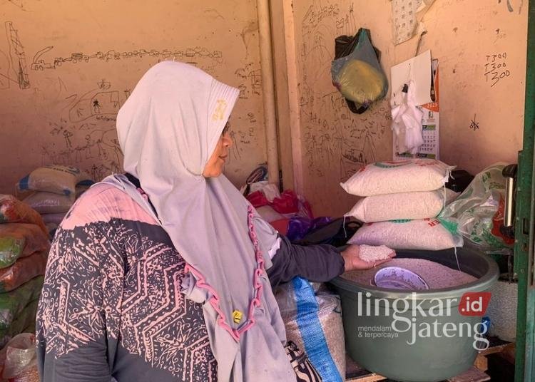 MENJUAL: Penjual beras di Pasar Bintoro mengecek stok dagangan. (M. Burhanuddin Aslam/Lingkarjateng.id)