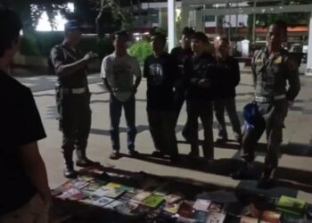Petugas Satpol PP saat berusaha menertibkan lapak baca gratis yang digelar komunitas Pustaka Malam Pati di Alun-alun Simpang Lima, Kabupaten Pati, pada Sabtu malam, 12 April 2025. (Dok. Lingkarjateng.id)