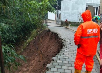 PANTAU SITUASI : Petugas BPBD Kota Salatiga melihat kondisi tabah longsor di Perum Residence RT 03 RW 05 Kelurahan Tegalrejo, Kecamatan Argomulyo, Minggu, 11 Mei 2025 sore. (Humas BPBD Salatiga/Lingkar jateng.id)