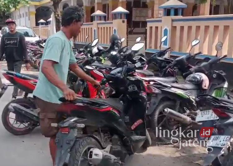 MEMARKIR: Juru parkir menata sepeda motor di lahan parkir liar depan Masjid Besar Kayen dan RSUD Kayen. (Setyo Nugroho/Lingkarjateng.id)