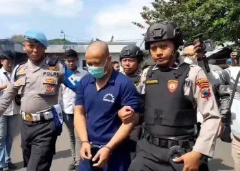 Tersangka, AW, saat digelandang petugas kepolisian untuk dihadirkan di konferensi pers di Mapolresta Pati pada Rabu, 30 Juli 2025. (Mutia Parasti/Lingkarjateng.id)