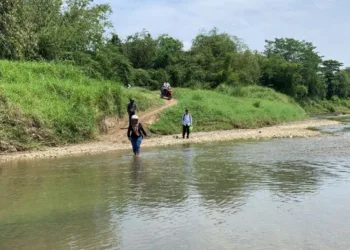 Warga Dukuh Tapak, Desa Kedunggading, Kecamatan Ringinarum, Kabupaten Kendal yang sedang melintas sungai karena pembangunan jembatan gantung tak kunjung terealisasi. (Arvian Maulana/Lingkarjateng.id)