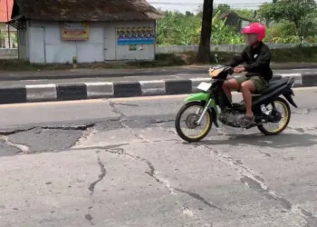 RUSAK: Seorang pengendara sepeda motor melintas di Jalan Pantura Demak-Kudus. (M. Burhanuddin Aslam/Lingkarjateng.id)