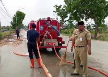 Petugas terkait saat melakukan pembersihan residu tanah dari truk proyek normalisasi Sungai Wulan di Jalan Raya Demak-Mijen, Rabu, 17 September 2025. (M. Burhanuddin Aslam/Lingkarjateng.id)