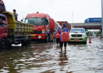 Petugas menyalurkan bantuan makanan kepada para sopir truk yang terjebak banjir di jalur Pantura Semarang-Demak, Jumat, 24 Oktober 2025. (Humas Pemprov Jateng/Lingkarjateng.id)
