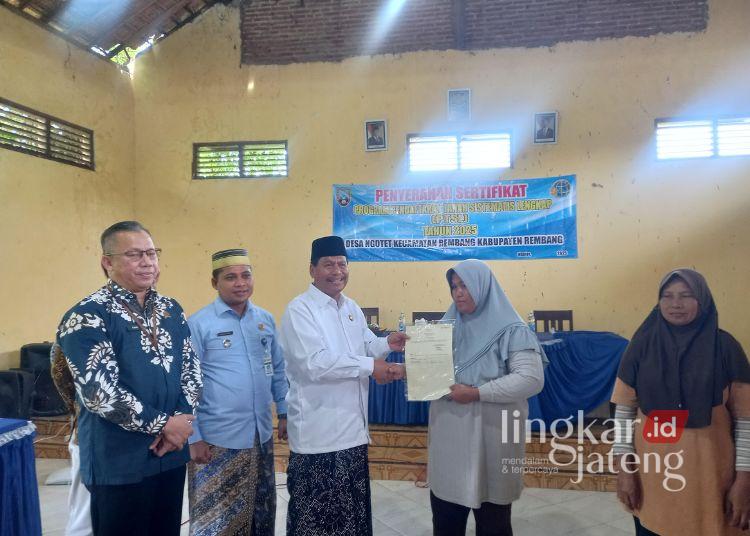 Bupati Harno didampingi Camat Rembang dan Kepala BPN Rembang menyerahkan sertifikat tanah dari program PTSL kepada warga Desa Ngotet di Balai Desa Ngotet, Kamis, 27 November 2025. (Muhammad Faalih/Lingkarjateng.id)