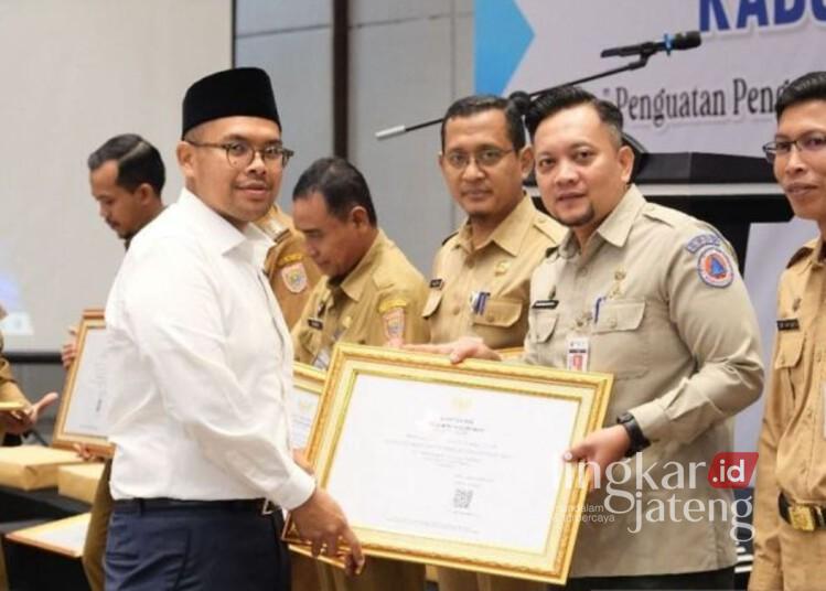 Bupati Batang, M. Faiz Kurniawan, menyerahkan piagam penghargaan kepada Pelaksana Tugas Kepala Dinas Kominfo Kabupaten Batang, Wawan Nurdiansyah, di Batang, Selasa, 2 Desember 2025. (Antara/Lingkarjateng.id)