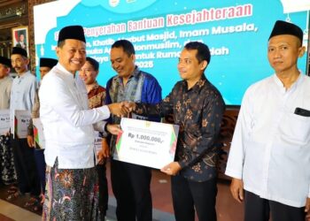 Bupati Kudus, Sam’ani Intakoris, menyerahkan secara simbolis bantuan kesejahteraan untuk pengurus rumah ibadah di Pendopo Kabupaten Kudus, Kamis, 18 Desember 2025. (Nisa Hafizhotus S./Lingkarjateng.id)