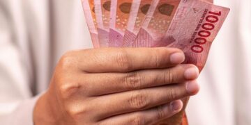 ILUSTRASI: Seseorang memegang uang pecahan Rp100.000. (Canva)