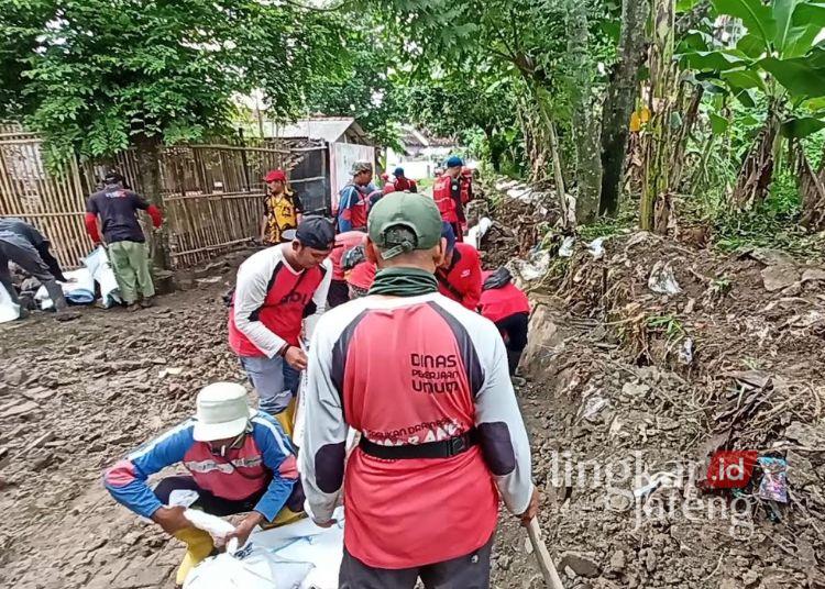 Talud Kerap Jebol, BBWS Sebut Sungai Plumbon Semarang Butuh Rehabilitasi Mendesak 25 Pekerja dari Dinas Pekerjaan Umum Kota Semarang bersama warga membersihkan sisa tanggul jebol di alirasn Sungao Plumbon turut RT 06 RW 04, Kelurahan Mangunharjo, Kecamatan Tugu, Kota Semarang pada Kamis, 11 Desember 2025. (Syahril Muadz/Lingkarjateng.id)