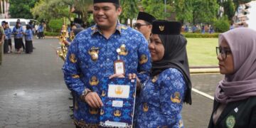 Wakil Bupati Jepara, M. Ibnu Hajar, menyerahkan hadiah kepada ASN berprestasi dalam upacara HUT KORPRI, DWP, dan Hari AIDS Sedunia di halaman Kantor Setda Jepara, Senin, 1 Desember 2025. (Tomi Budianto/Lingkarjateng.id)