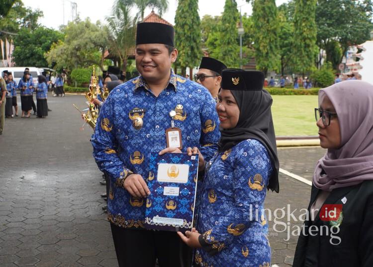 Wakil Bupati Jepara, M. Ibnu Hajar, menyerahkan hadiah kepada ASN berprestasi dalam upacara HUT KORPRI, DWP, dan Hari AIDS Sedunia di halaman Kantor Setda Jepara, Senin, 1 Desember 2025. (Tomi Budianto/Lingkarjateng.id)