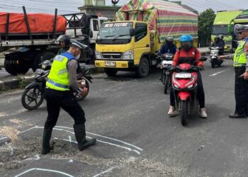 Petugas Satlantas Polres Demak memberikan tanda di ruas jalan yang rusak. Foto : M. Burhan/ Lingkar Jateng
