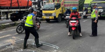 Petugas Satlantas Polres Demak memberikan tanda di ruas jalan yang rusak. Foto : M. Burhan/ Lingkar Jateng