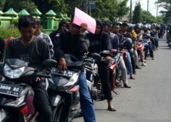 Sejumlah warga Tegal, Jawa Tengah duduk di atas kendaraannya saat antre pemutihan pembayaran pajak kendaraan bermotor (PKB) di Samsat Slawi pada Rabu, 9 April 2025. (Antara)