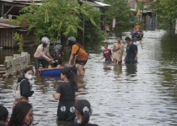 Warga Desa Mulyorejo Kecamatan Tirto melintasi genangan banjir yang merendam permukiman akibat luapan Sungai Sengkarang di Kabupaten Pekalongan, Sabtu, 24 Januari 2026. (Fahri Akbar/Lingkarjateng.id)