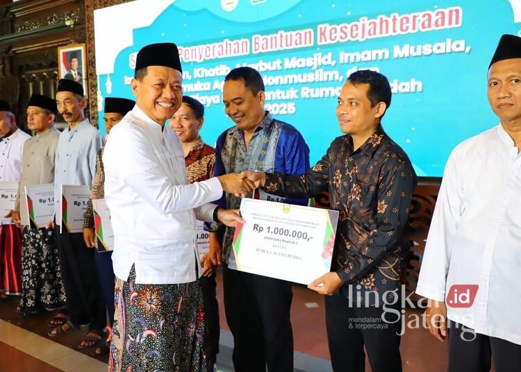 Bantuan Kesejahteraan Pemuka Agama di Kudus Tahun 2026 Dianggarkan Rp5,8 Miliar 25 Bupati Kudus, Sam'ani Intakoris, menyerahkan bantuan kesejahteraan bagi pemuka agama di Pendopo Kabupaten Kudus pada 2025 lalu. (Nisa Hafizhotus S./Lingkarjateng.id)