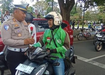 Kasat Lantas Polres Salatiga AKP Henry Sulistyanta DS memberikan bunga dan coklat kepada pengendara motor yang tertib lalu lintas yang melintas di depan Mapolres, Senin, 2 Februari 2026. (Angga Rosa/Lingkarjateng.id)