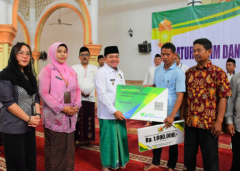 Plt. Bupati Pekalongan, Sukirman, menyerahkan bantuan perlindungan jaminan sosial ketenagakerjaan kepada pekerja rentan di Masjid Al Muhtarom Kajen, Selasa pagi, 21 April 2026. (Fahri Akbar/Lingkarjateng.id)
