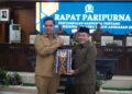 Bupati Jepara, Witiarso Utomo, menyerahkan dokumen Rancangan Peraturan Daerah (Ranperda) Pertanggungjawaban Pelaksanaan APBD Tahun Anggaran 2025 kepada Ketua DPRD Jepara, Agus Sutisna, dalam rapat paripurna, Senin, 22 Juni 2026. (Tomi Budianto/Lingkarjateng.id)