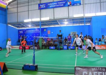 Pelaksana Tugas (Plt) Bupati Pekalongan, Sukirman (berseragam oranye), ikut bermain bulutangkis pada pembukaan Kejurkab Bulutangkis Bhayangkara Cup 2026 di Gedung Olahraga Badminton Wicaksana Leghawa Polsek Kajen, Jumat, 26 Juni 2026. (Fahri Akbar/Lingkarjateng.id)