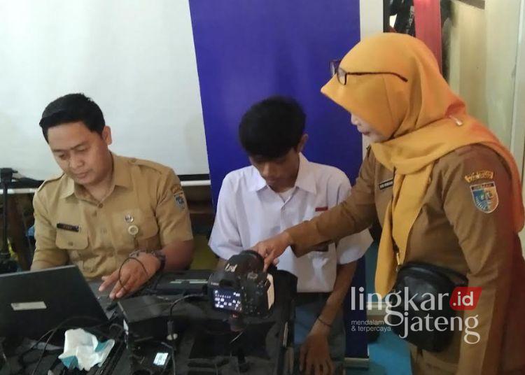 Dindukcapil Demak Sasar 42 Sekolah Layani Siswa Bikin KTP dan Adminduk Lainnya 25 Petugas Dinas Kependudukan dan Pencatatan Sipil (Dindukcapil) Kabupaten Demak mendampingi siswa rekam data pembuatan KTP. (Burhanuddin Aslam/Lingkarjateng.id)