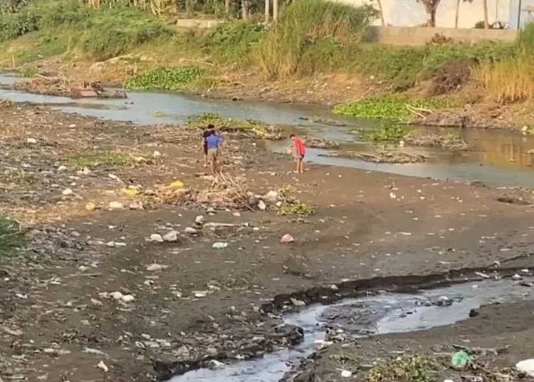 Sejumlah warga berjalan di tengah Sungai Silogonggo Pati yang mengering. (Fahtur Rohman/Lingkarjateng.id)
