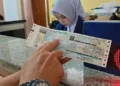 ILUSTRASI: Seorang wajib pajak menunjukkan dokumen pembayaran pajak kendaraan. (Fahri Akbar/Lingkarjateng.id)