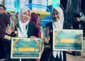 Zumrotul Luthfiyyah dan adiknya, Durratul Muqoffa, menunjukkan piala dan penghargaan usai menjadi juara dalam MTQ Nasional ke-31 tahun 2026 di Kota Semarang. (Vicky Rio/Lingkarjateng.id)