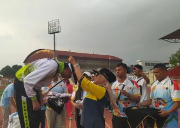 Ketua Umum Pengurus Provinsi (Pengprov) Persatuan Drumband Indonesia (PDBI) Jawa Tengah, Dyah Kartika Permanasari, mengalungkan medali kepada atlet pemenang kompetisi cabor drumband pada Porprov Jateng di Stadion Sultan Fatah Kabupaten Demak pada Sabtu, 24 Oktober 2026. (Ahmad Abror/Lingkarjateng.id)